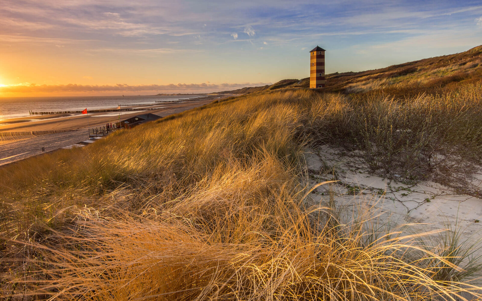 Beautiful summer evening with sunset on top of a dune near Dishoek, with a view of a beacon of light.
