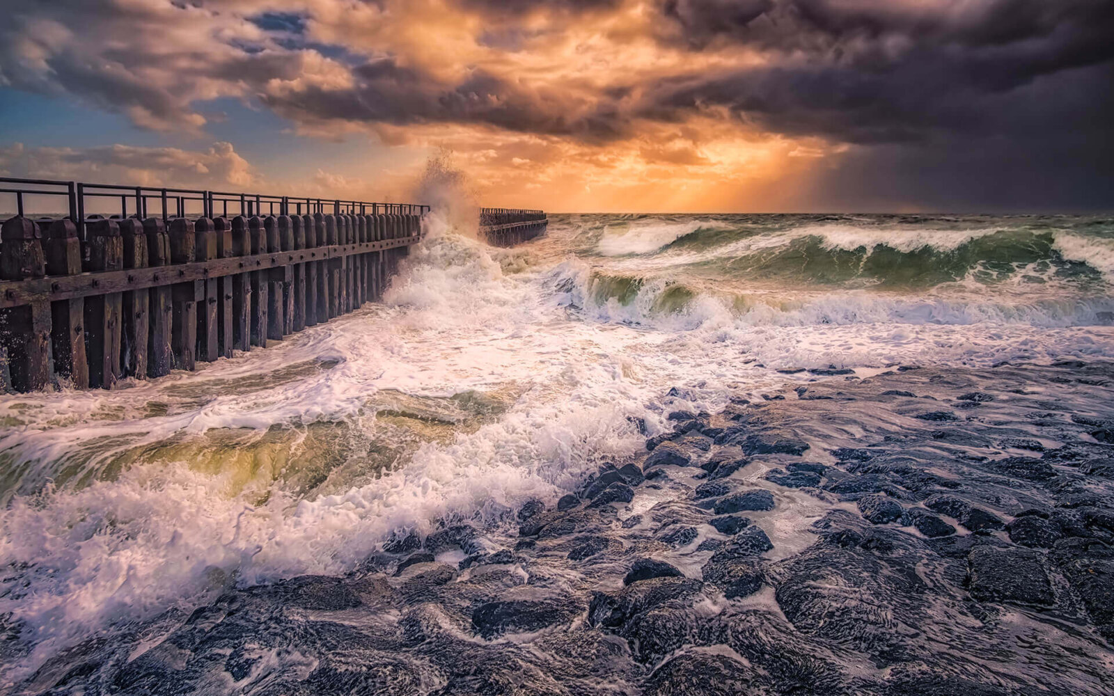 A rolling wave against the dike at Westkapelle, under stormy conditions with beautiful rays of sunshine.