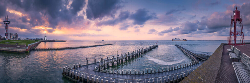 A panorama of Vlissingen, including a lighthouse and Oranjemolen, made from the fortress during a sunrise.