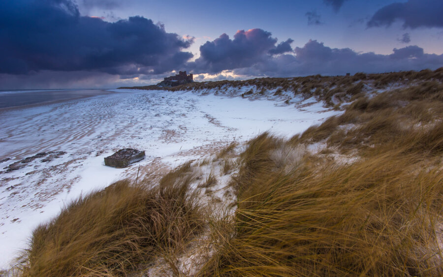 One early morning, at sunrise, there was snow on the beach at Bamburgh Castle.