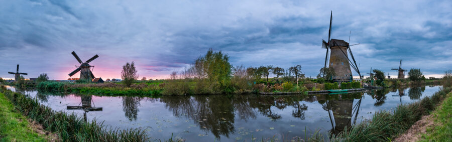 The sun tries to break through the dense cloud cover above the Kinderdijk windmills with the last rays of the day.