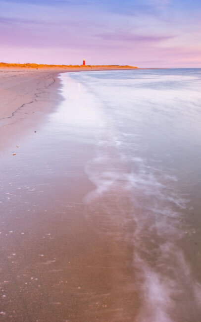 Sunrise on the Texel beach with a view of the lighthouse.