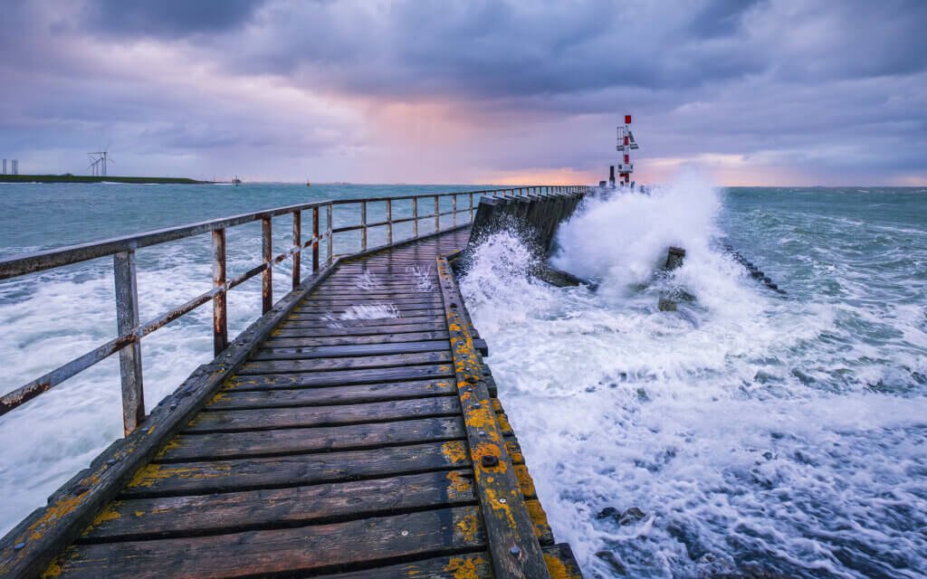 With wind force 7 on the Western Scheldt in Vlissingen. The waves break against the jetty at sunrise.