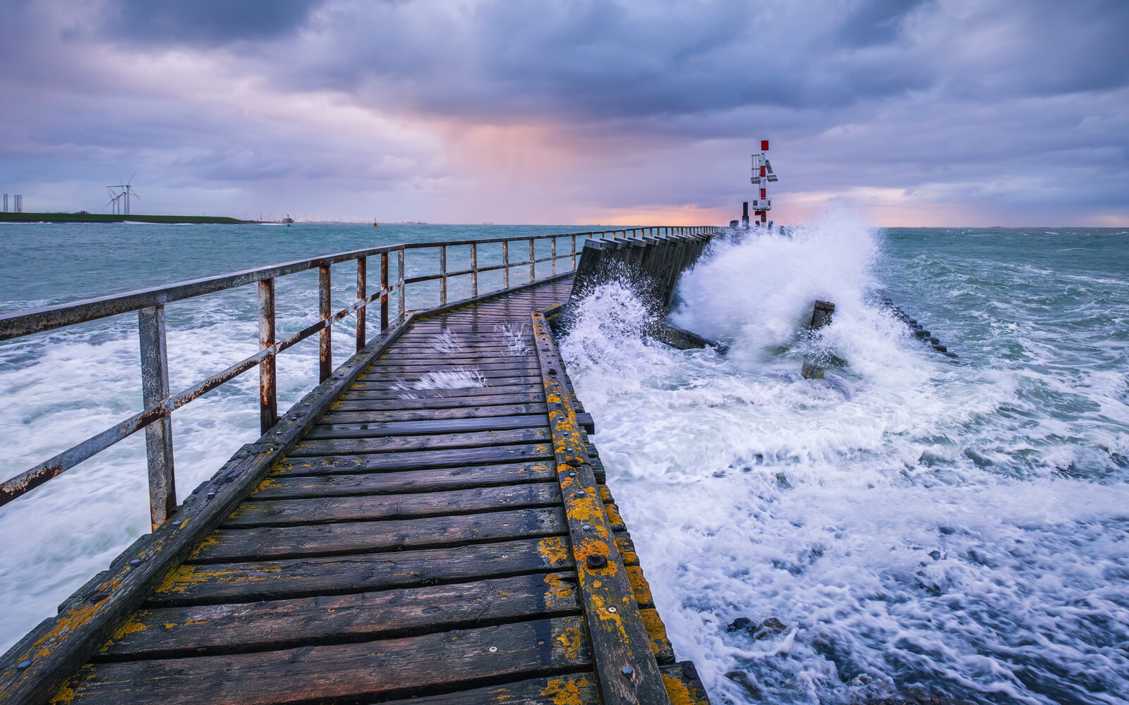 With wind force 7 on the Western Scheldt in Vlissingen. The waves break against the jetty at sunrise.