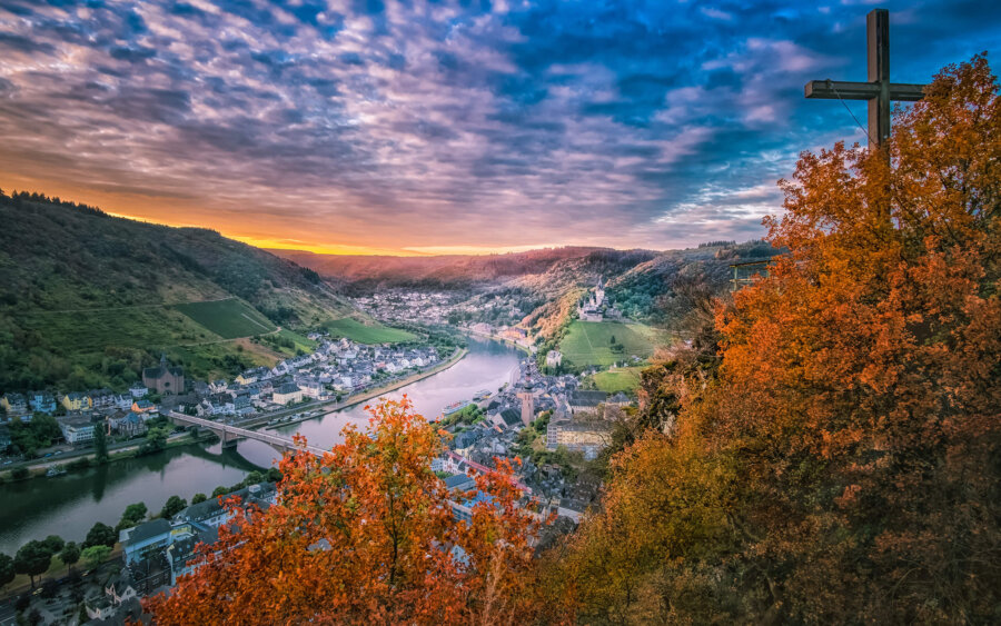 Cochem Early one morning, with a view of the city of Cochem from the Pinnerkreuz observation platform. We see Cochem Castle, St. Martin's Church, the Skagerak Bridge, and the Moselle River at sunrise.