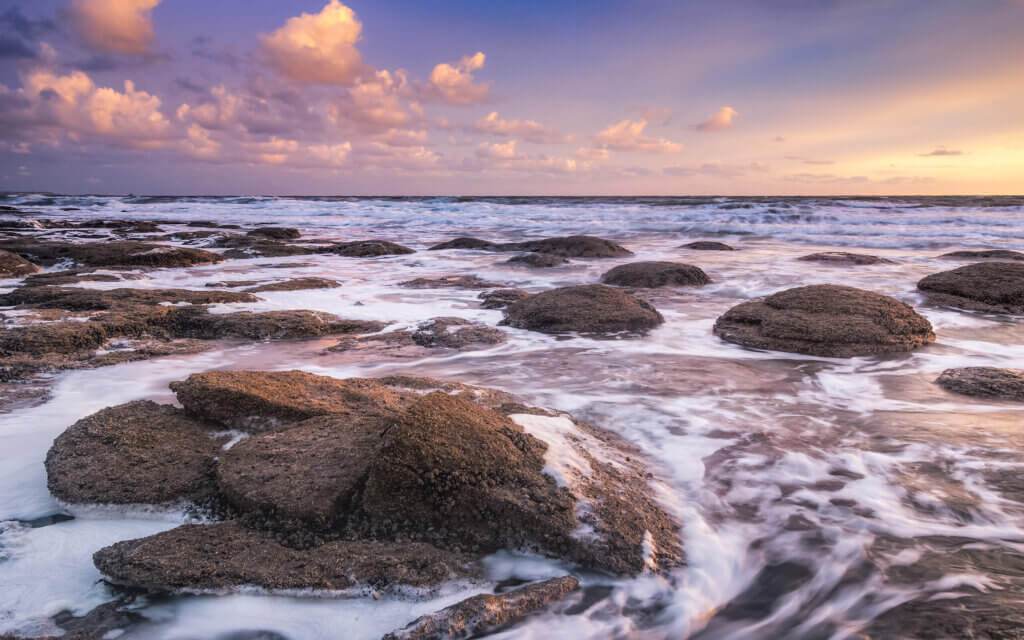 Beautiful sunset on the rocky coast near Ambleteuse in France. The sea rolls gently around the rocks.