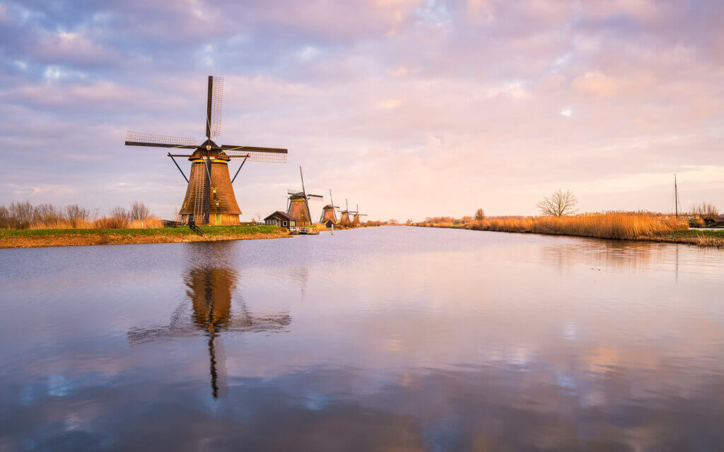 Beautiful, peaceful, and calm spring sunset at the Kinderdijk windmills. Lovely reflection of the windmill and the clouds in the stream.